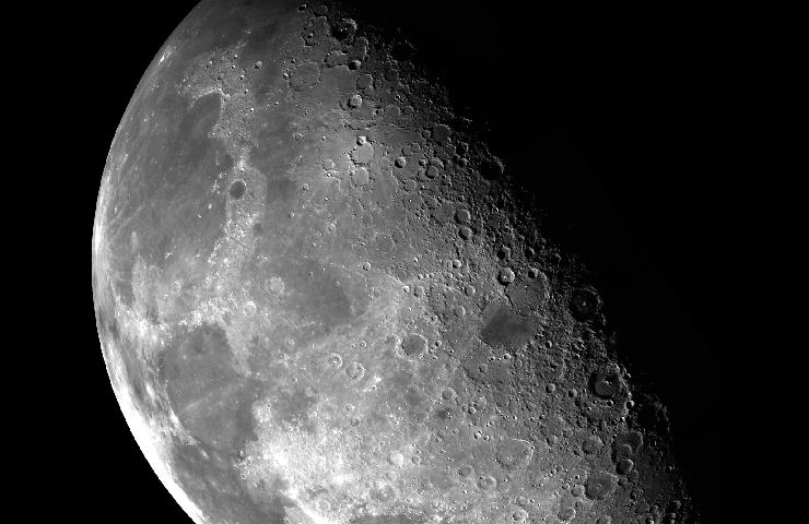 Immagine bianca e nera della luna sul grigio con una grande ombra a destra