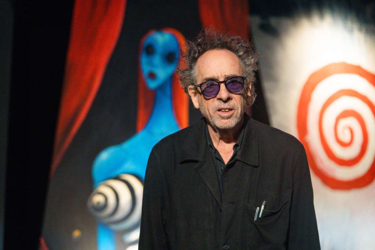 Tim Burton con dietro i suoi disegni