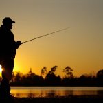 Un uomo a pesca al calar della notte