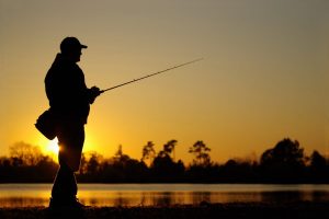 Un uomo a pesca al calar della notte